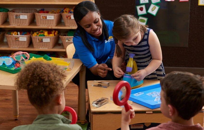 Teacher helping child look through microscope for a STEAM activity