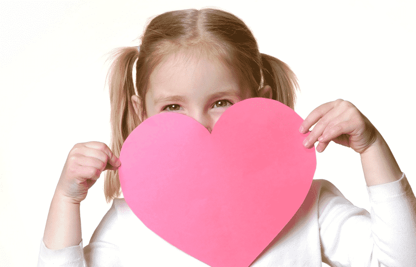 Preschool girl holding a pink Valentine's Day heart card