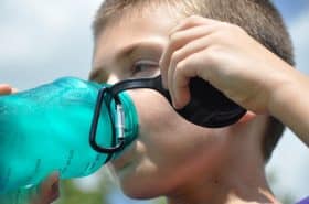 school-age boy drinking water to stay hydrated