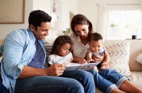 family reading a children's book together on couch