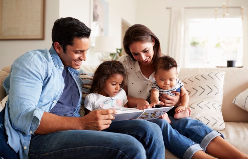 family reading a children's book together on couch