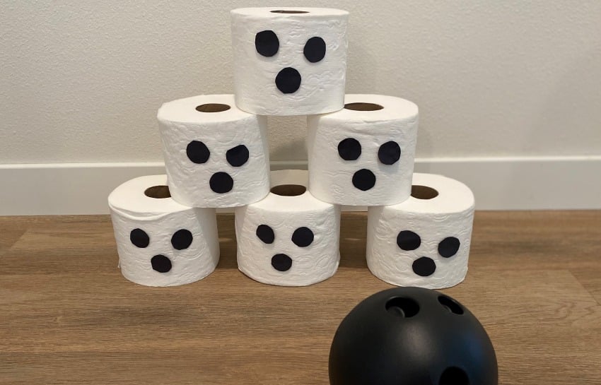 Halloween bowling using toilet paper roll ghosts and a plastic ball