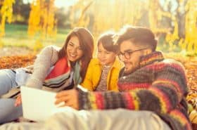 family reading a book outside in the fall