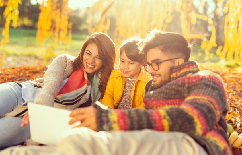 family reading a book outside in the fall