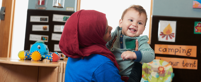 Teacher holding infant child during daycare