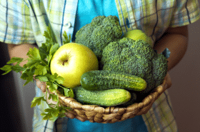 child holding bowl of green fruits and green vegetables