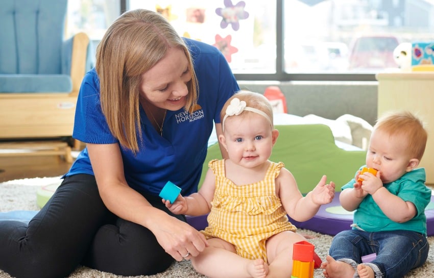 infant daycare teacher safely caring for two infants at New Horizon Academy