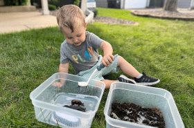 Toddler child washing toy farm animals for a sensory bin activity