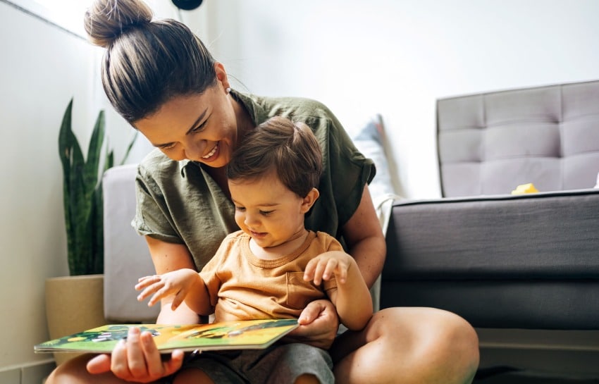 mother reading a storybook to her toddler on her lap