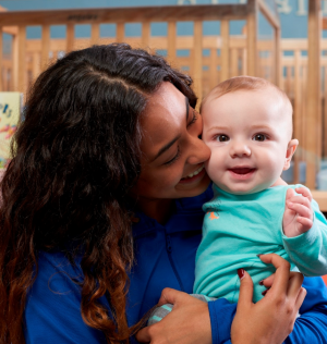 http://daycare%20teacher%20hugging%20infant%20in%20classroom