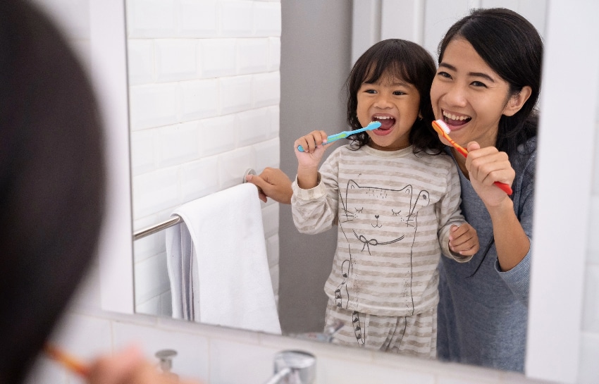 Parent and child brushing teeth together while practicing pediatric oral health tips