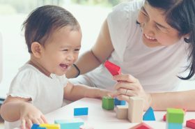 Mother interacting with baby as she practices serve and return interaction while playing with blocks