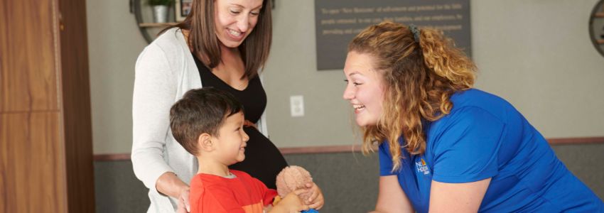 Pregnant mother touring a daycare with her preschool son