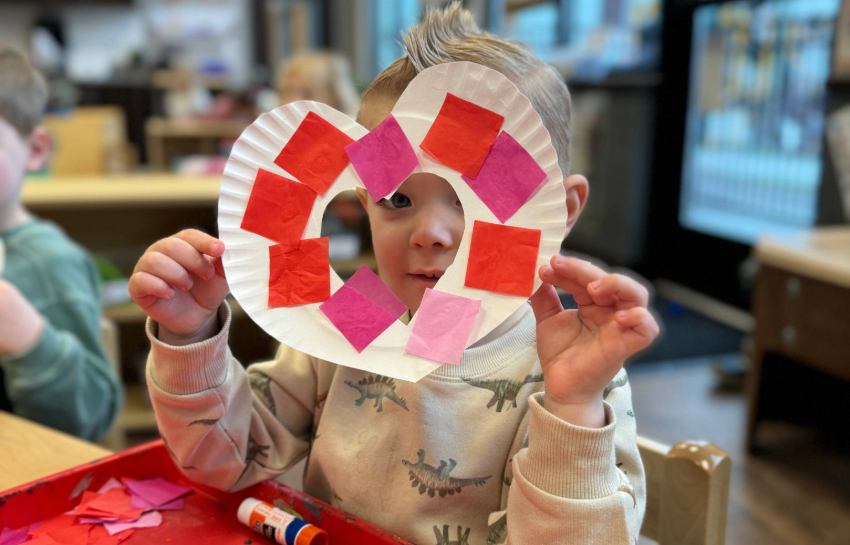 Preschool boy holding homemade Valentine's Day heart wreath craft